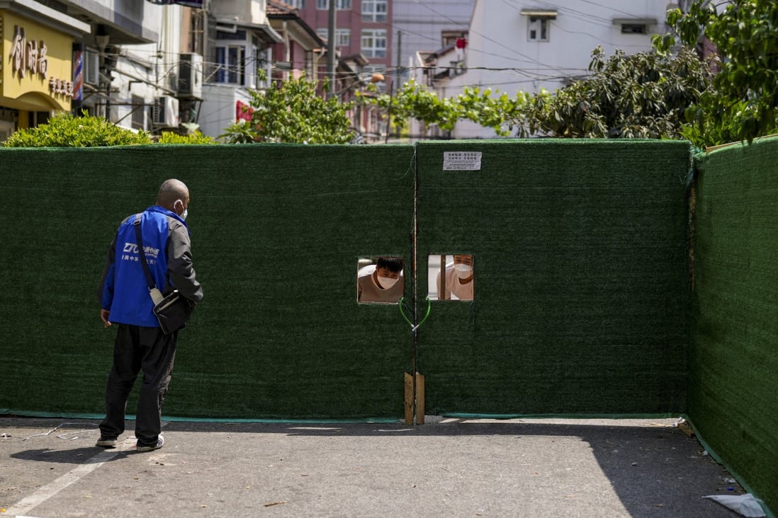 On Tuesday, May 3, people peer through a barrier used to lock down a residential area in Shanghai. Photo: Reuters