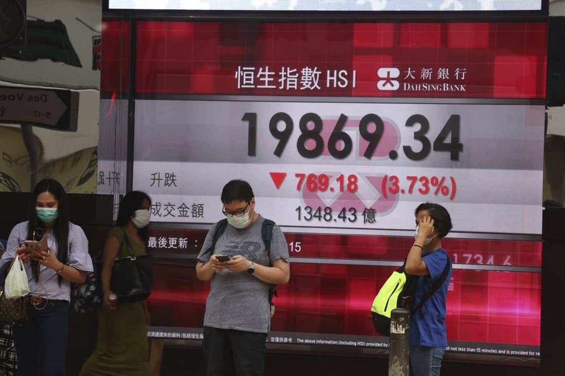 People passing by a board showing the Hang Seng Index in Central, Hong Kong on April 25. Photo: K. Y. Cheng