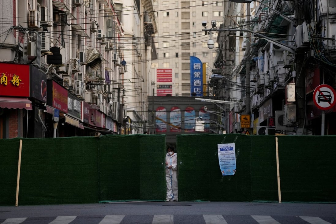 A worker in a protective suit locked a barrier of a residential area in Shanghai on May 4, 2022. Photo: Reuters