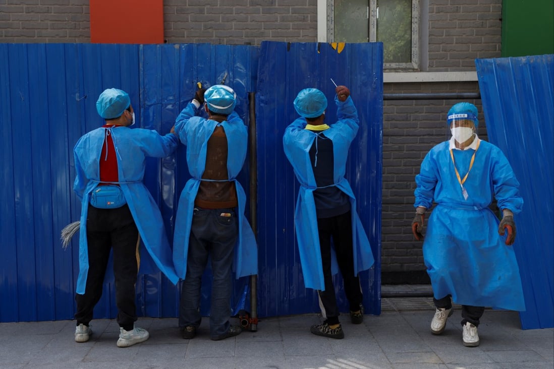 Workers wearing personal protective equipment install a barricade around a residential area under lockdown in Beijing on Wednesday amid a Covid-19 outbreak. Photo: Reuters