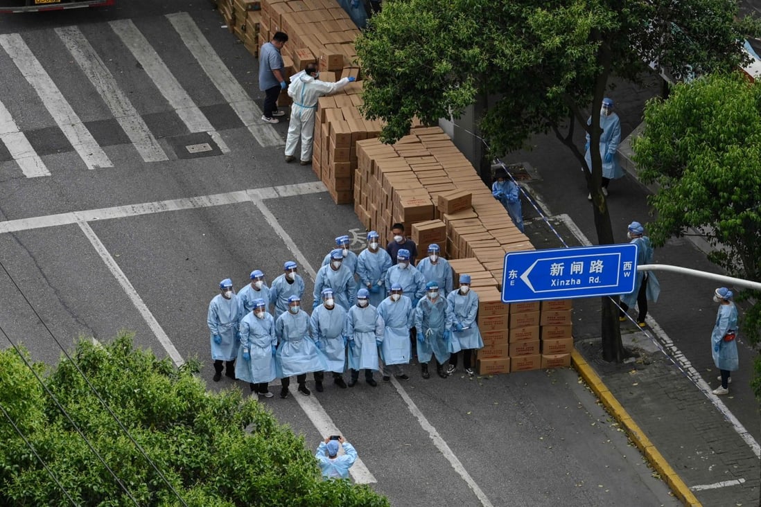 Workers wearing protective gear stand next to boxes with food to be delivered in a neighborhood during a Covid-19 coronavirus lockdown in the Jing’an district in Shanghai on May 7. Photo: AFP