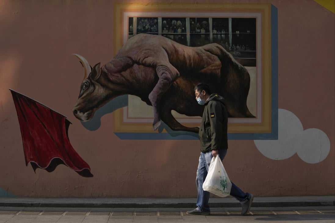 A man carrying a bag of groceries walks past a mural depicting an iconic financial market bull statue, near the central business district in Beijing, on April 18. Photo: AP 