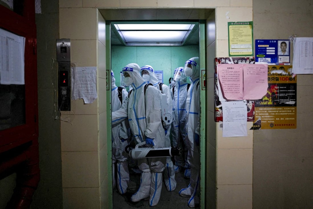 Workers in protective suits take a lift to disinfect a residential area during lockdown, amid the coronavirus  pandemic, in Shanghai on May 18. Photo: Reuters