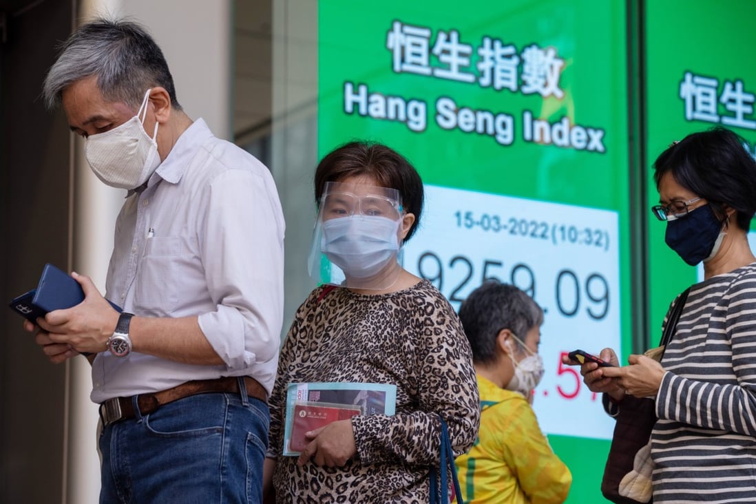 Pedestrians wearing protective masks pass an electronic screen displaying the Hang Seng Index in Hong Kong. Photo: Bloomberg