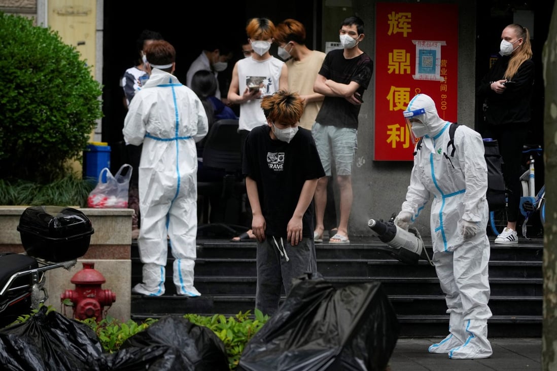 A worker in a protective suit disinfects a person during lockdown in Shanghai on May 20. Photo: Reuters