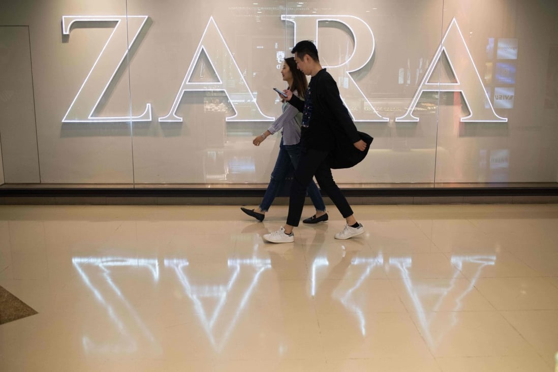 Two people walk past the Zara clothing brand name at a shopping mall in Beijing. Photo: AFP