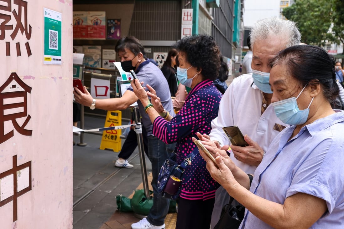 Elderly residents use the “Leave Home Safe” app on their smartphones to scan a QR code to enter a market in Tai Po. Photo: K. Y. Cheng