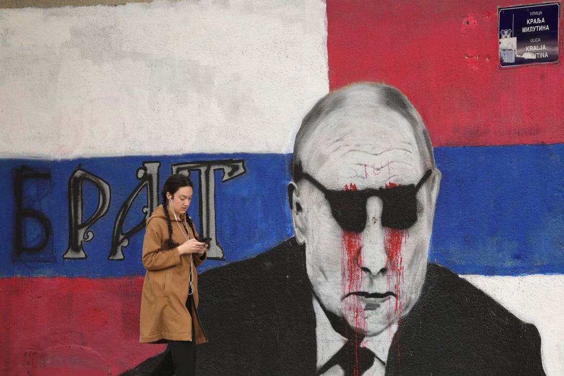A woman passes by a mural depicting Russian President Vladimir Putin, vandalised with paint, in Belgrade, Serbia, this month. Photo: AP 