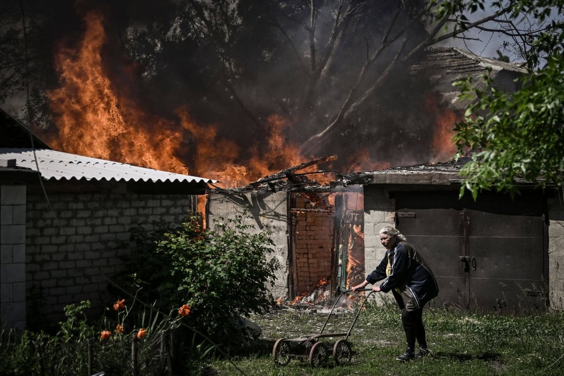 An elderly woman walks away from a burning house garage after shelling in the city of Lysychansk in the eastern Ukrainian region of Donbas. Photo: AFP