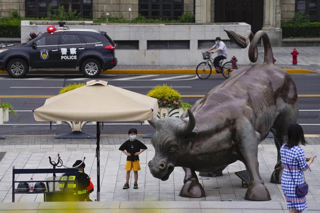 A child poses for a photo near a sculpture of a bull along the bund in Shanghai on Wednesday. China’s largest city reopened after a two-month lockdown. Photo: AP Photo
