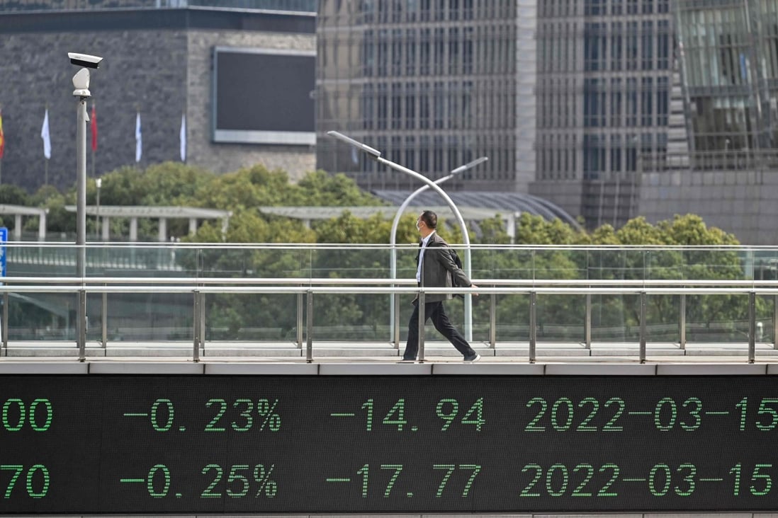 A man crosses a bridge with a stocks indicator board in Shanghai’s financial district on March 16. Photo: AFP