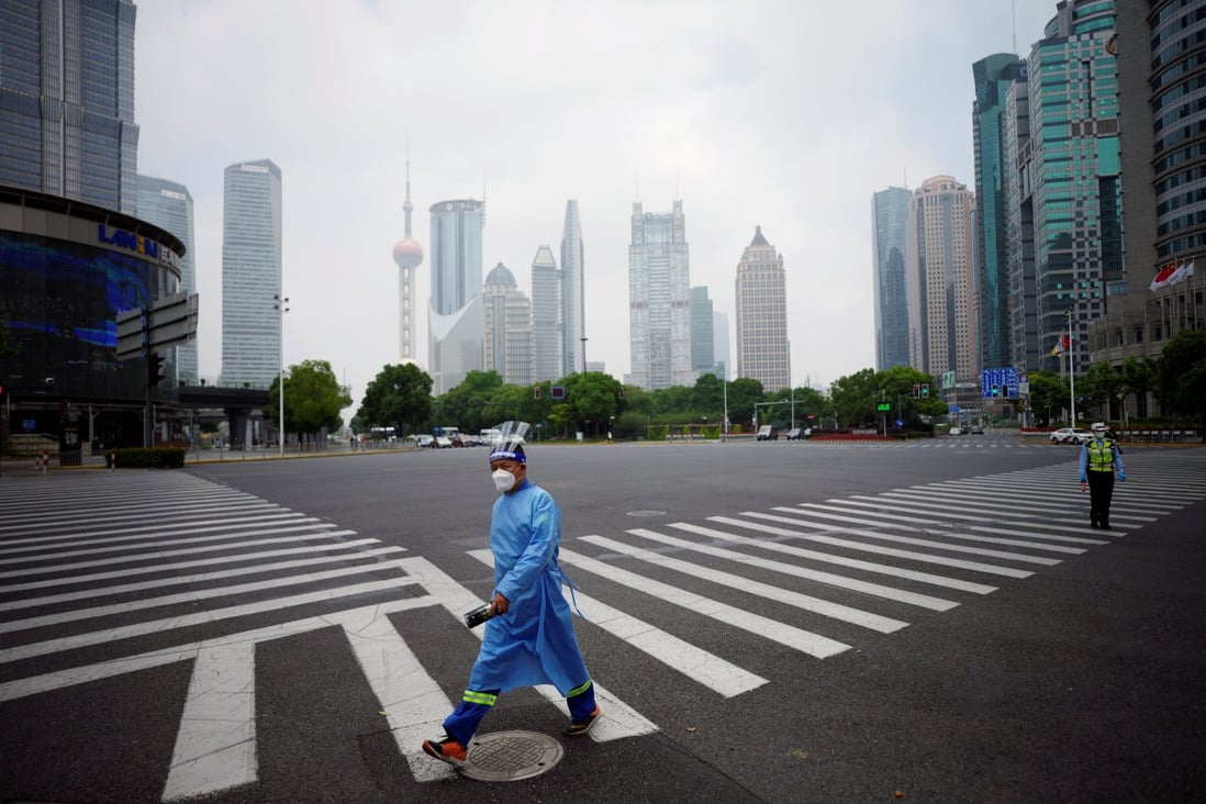 A worker in a protective suit walks on a pedestrian crossing at an intersection in Shanghai’s Lujiazui financial district on June 2, 2022. China’s rigid Covid-19 control measures have been driving reduced carbon emissions since March this year. Photo: Reuters 