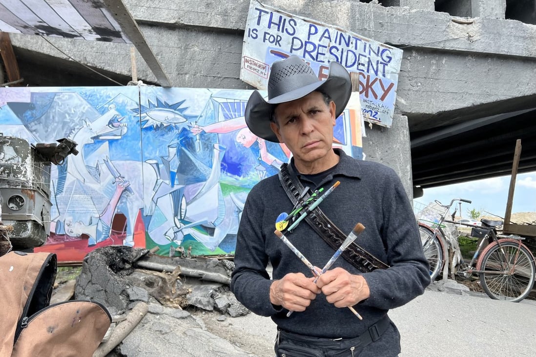 Roberto Marquez, a Mexico-born artist living in the US, working on a Picasso-style painting below a blown-up bridge in Irpin, Ukraine. Photo: TNS