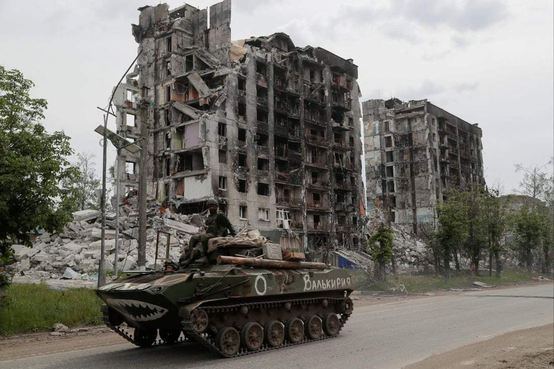 Service members of pro-Russian troops drive an armoured vehicle along a street past a destroyed residential building. Photo: Reuters