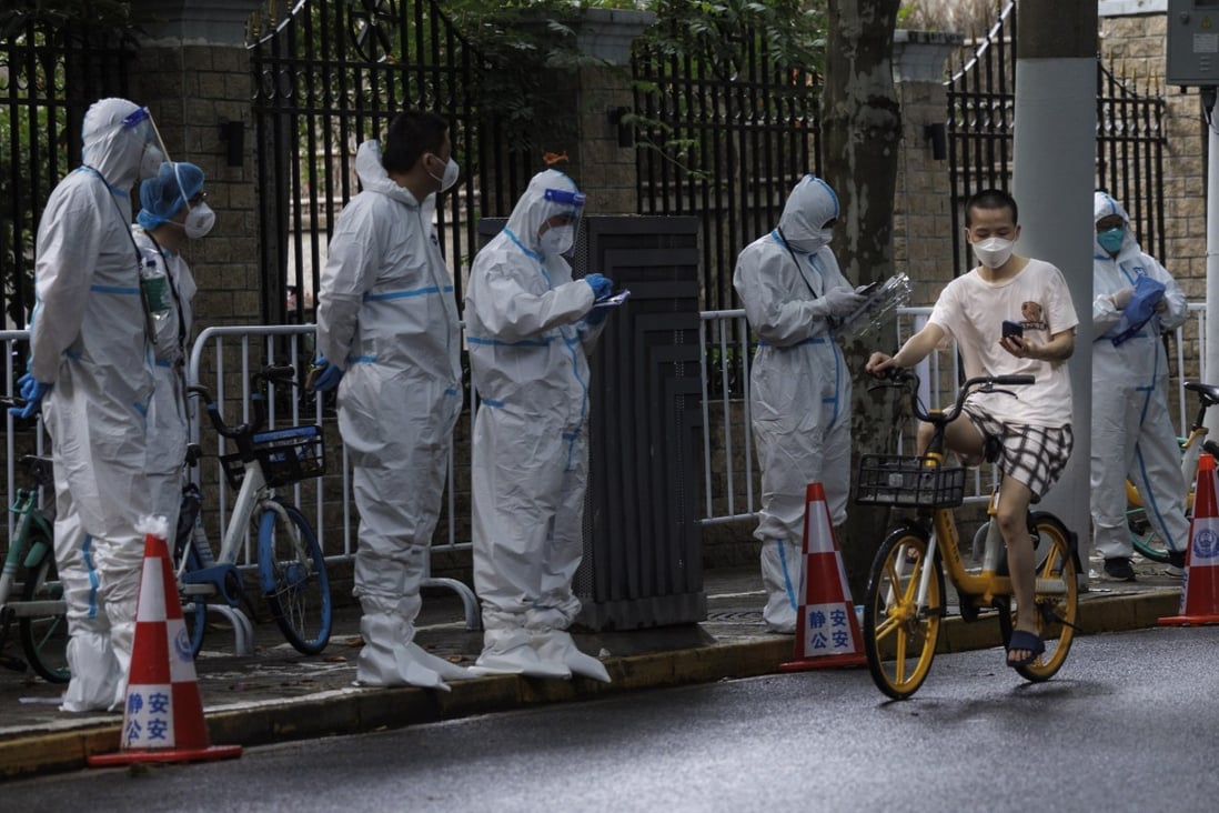 A man rides a bike past workers in protective gear in Shanghai on June 4 as the city deals with new, sporadic community outbreaks of Covid-19. Photo: EPA-EFE