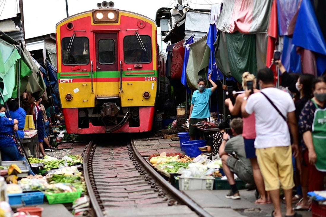 Vendors and visitors stand out of the way as a passenger train passes through Mae Klong Railway Market in Samut Songkhram province. Photo: AFP