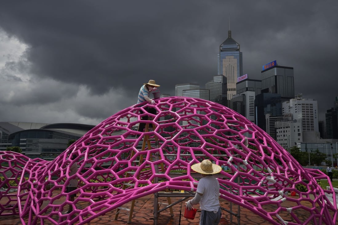 Workers wearing Covid-19 face masks paint a science-themed art installation at a Hong Kong waterfront park on Monday, ahead of celebrations for the 25th anniversary of Hong Kong’s handover to China. Photo: AP