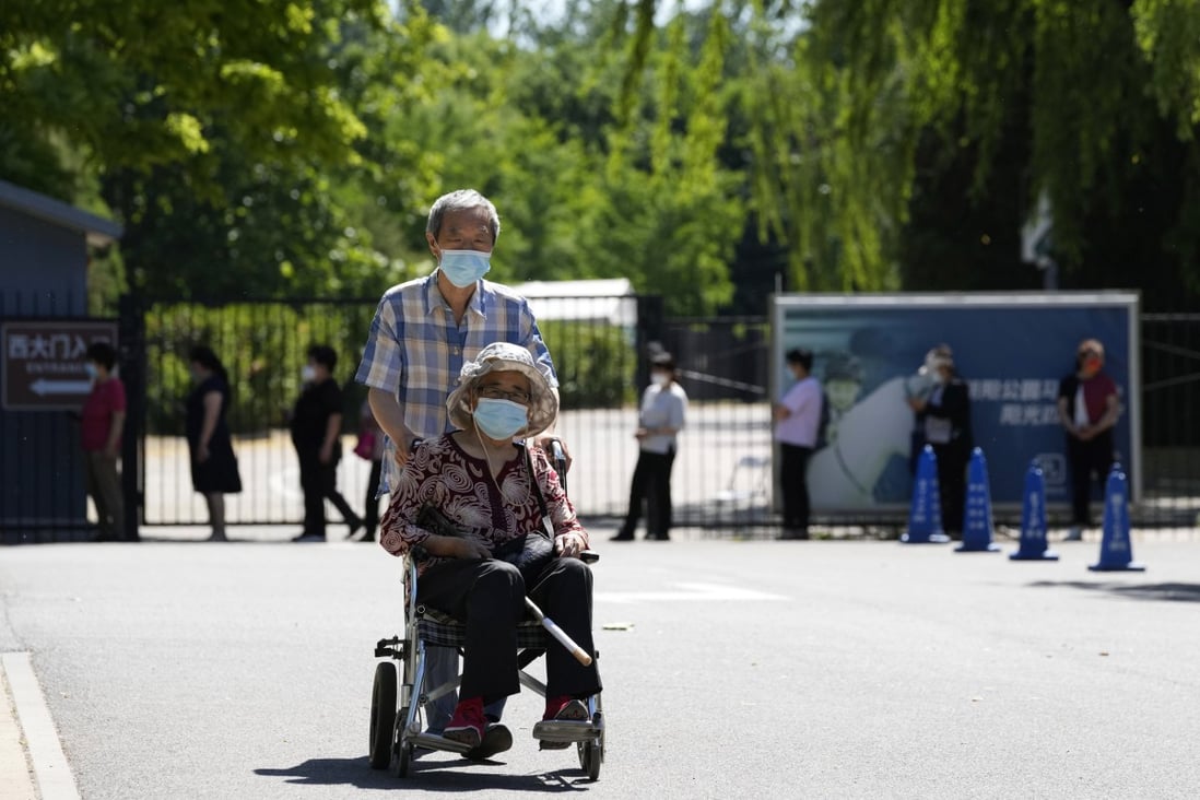 A man pushes an elderly woman past a line for Covid-19 testing on May 25 in Beijing. Photo: AP 
