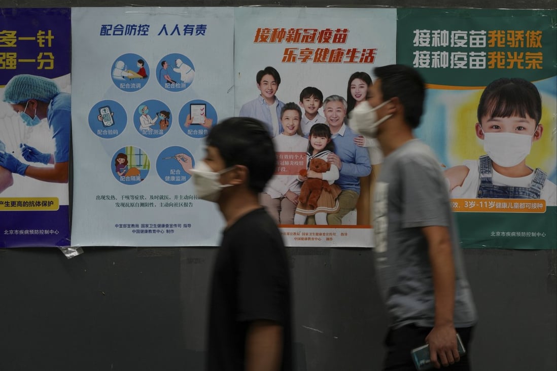 Residents wearing face masks walk past a wall displaying posters encouraging people to get vaccinated against Covid-19 in Beijing, June 9, 2022. Photo: AP
