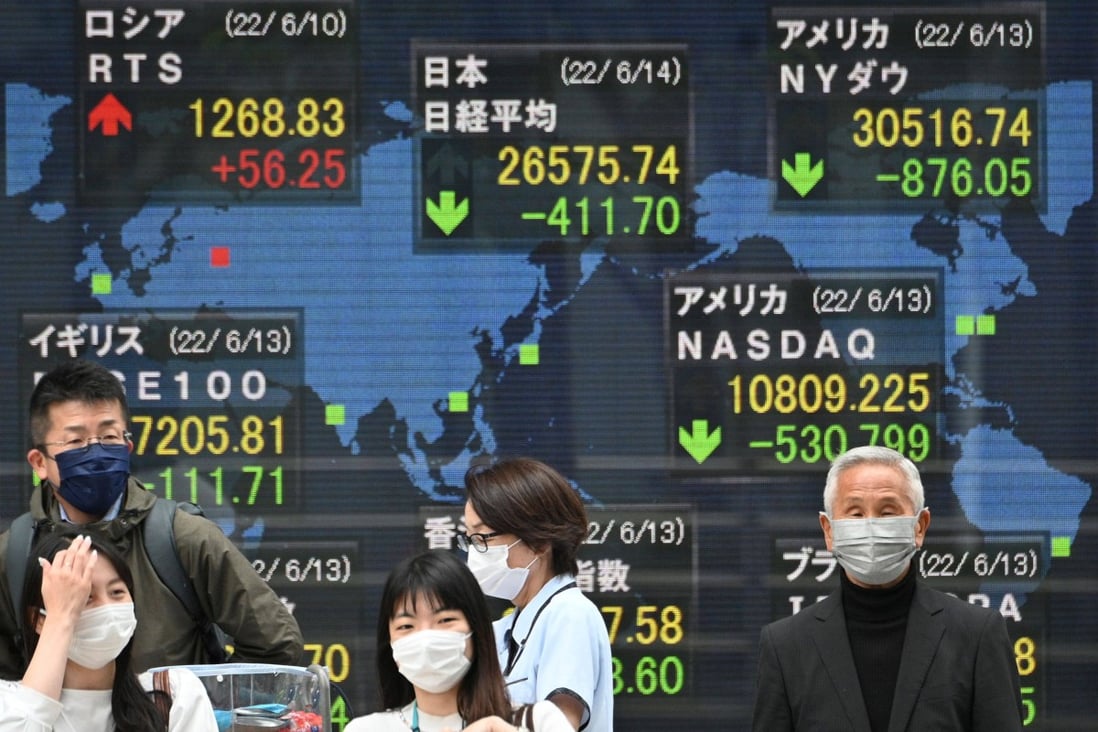 Pedestrians in front of an electronic quotation board displaying the numbers of the world’s stock market in Tokyo on June 14, 2022. Photo: AFP.