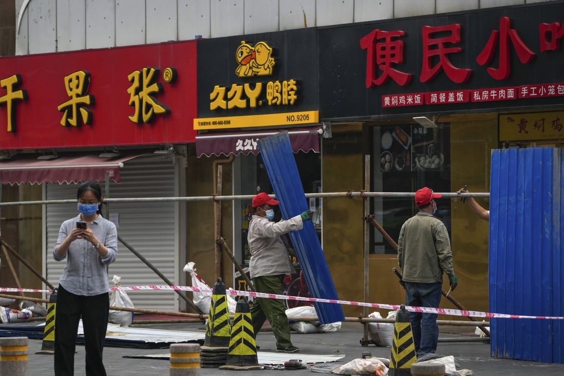 Workers set up metal barriers around closed retail shops and restaurants in Beijing on Sunday as authorities try to stop the spread of recent infections. Photo: AP