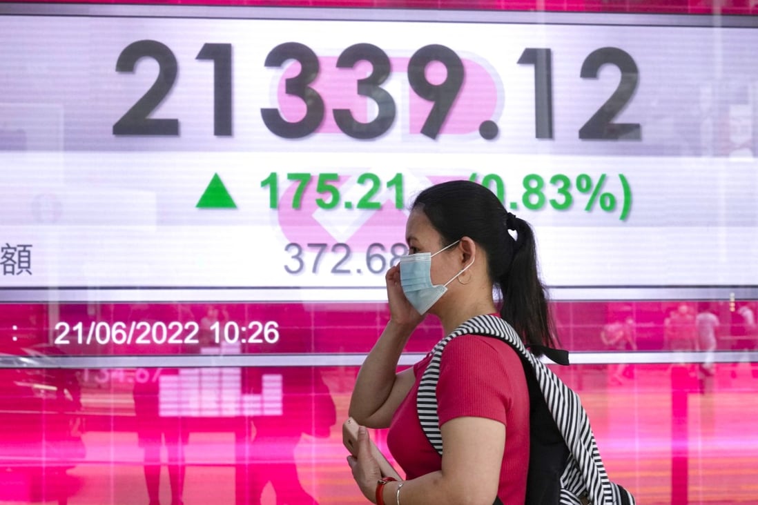 A woman walks past a bank’s electronic board showing the Hong Kong share index in Hong Kong on June 21, 2022. Photo: AP