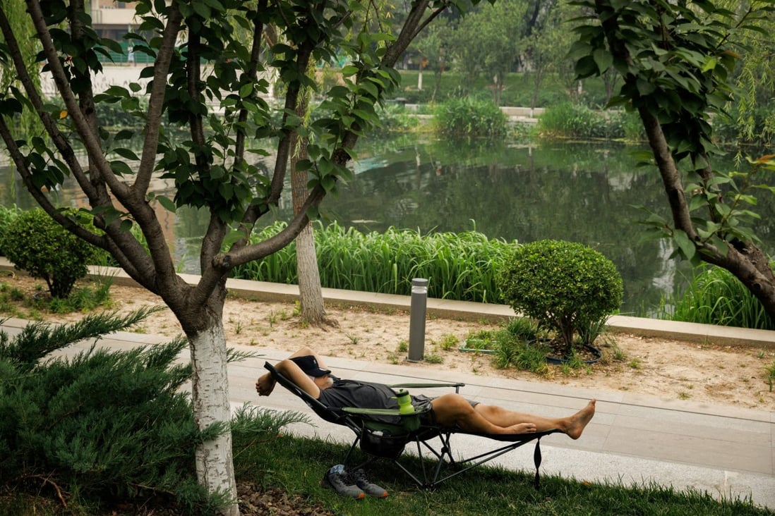 A man rests near a canal in Beijing on Tuesday. Heatwaves in northern and central China have led to record power demand this week. Photo: Reuters