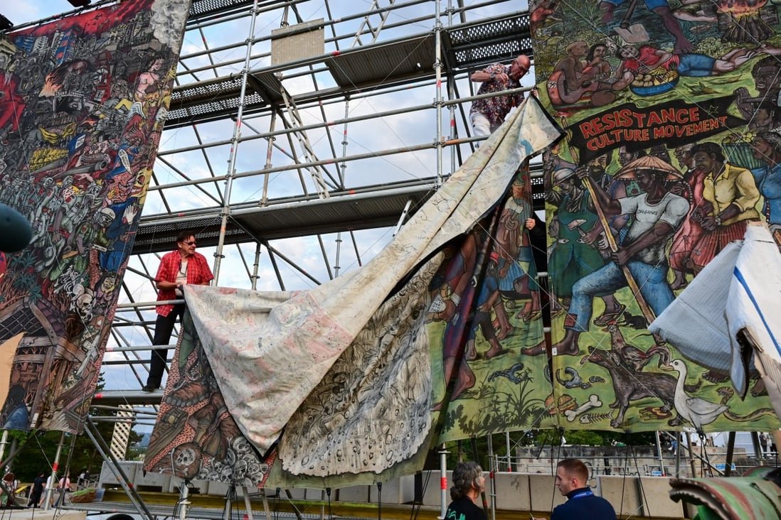 Staff take down the controversial ‘People’s Justice’ banner by the Indonesian artist collective Taring Padi at the Documenta art show in Kassel. Photo: Uwe Zucchi/dpa