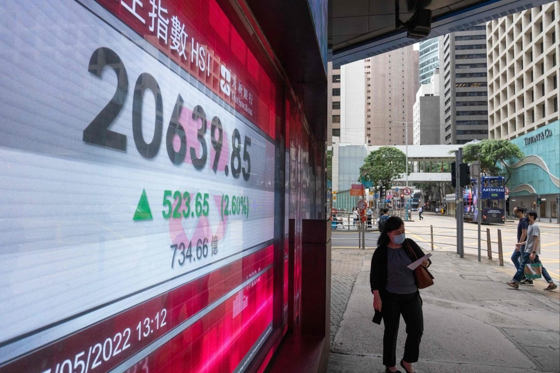 A woman walks past an electronic display showing the Hang Seng Index in the Central district of Hong Kong on May 27. Photo: AFP