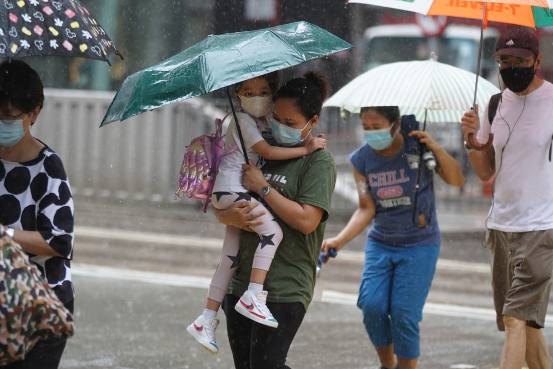 A woman carries a child during heavy showers in Tin Hau on August 19, 2021. Many Hong Kong women are able to join the workforce thanks to the labour of domestic helpers. Photo: Sam Tsang