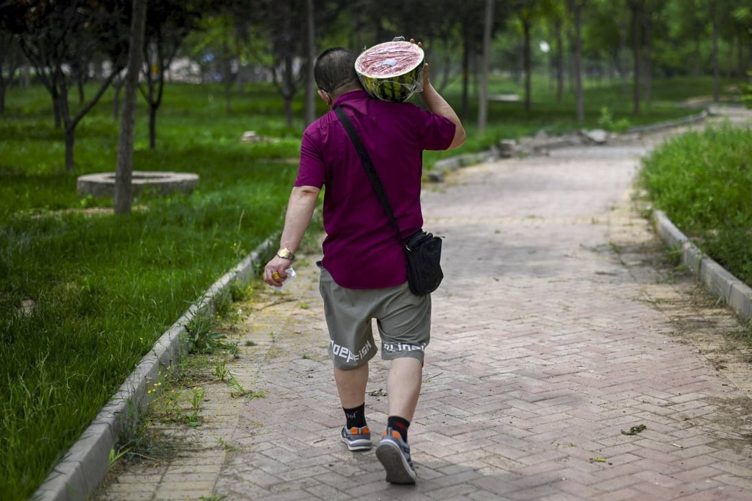 A man carrying a watermelon walks along a path in Beijing on June 21, 2022. Photo: AFP