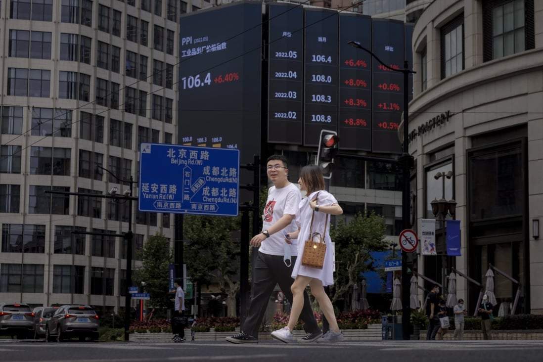 People walk in front of the jumbo screen showing the latest economic and stock updates in Shanghai on June 23. Photo: EPA-EFE
