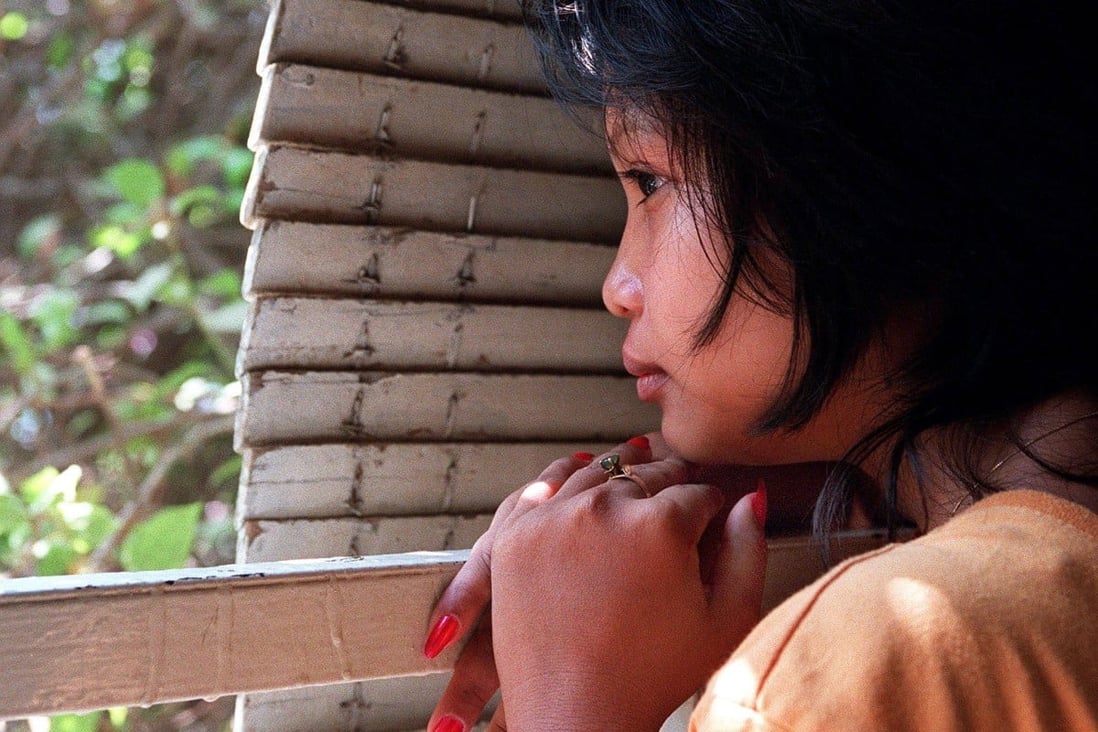 A Cambodian girl rescued from a brothel where she was forced to work hides behind shutters at a house in Phnom Penh. Photo: AFP