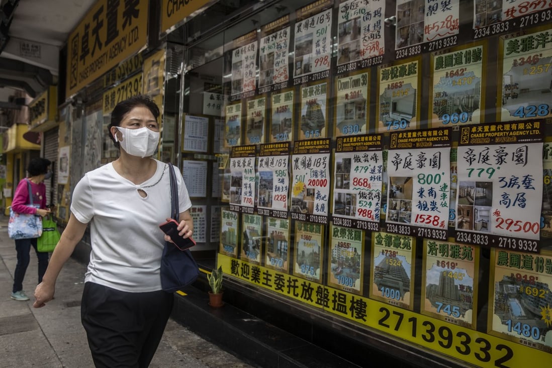 A woman walks past property listings in the window of a real estate agency in Hong Kong on May 13, 2022. Photo: AFP