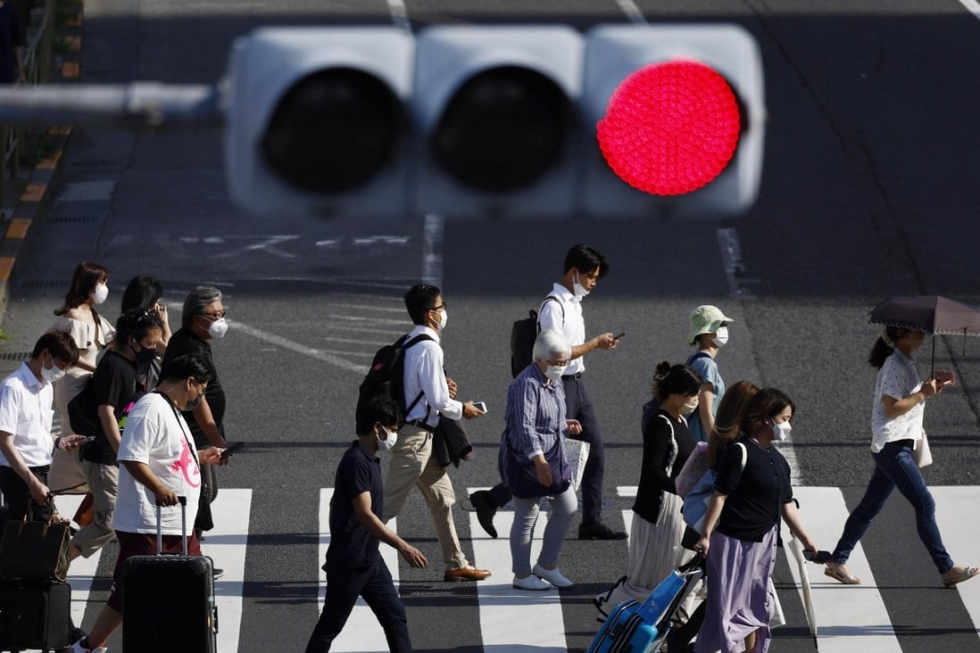 People wear face masks for protection against the coronavirus walk on a pedestrian crossing in Tokyo. Japan set a national record of more than 200,000 coronavirus cases on Saturday. Photo: Kyodo