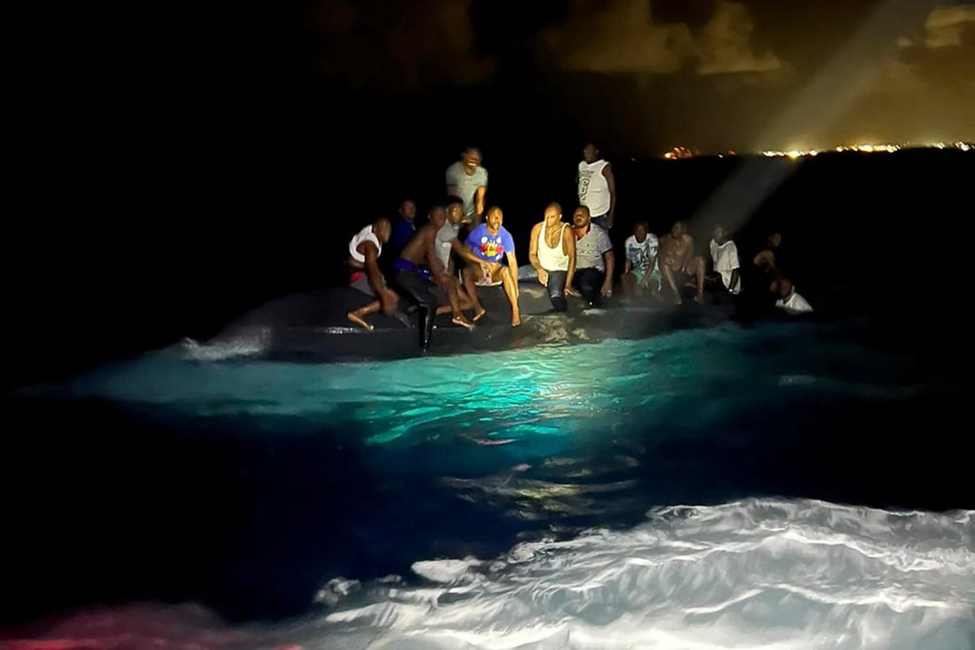 Survivors of a migrant boat that capsized perch on the overturned vessel off the coast of New Providence island, Bahamas on Sunday. Photo: Royal Bahamas Defence Force / Handout via Reuters