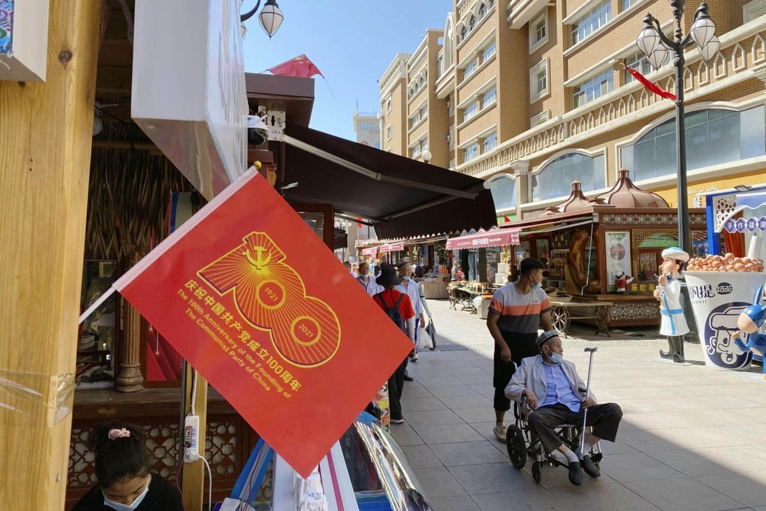 A red flag marks the 100th anniversary of the founding of the Chinese Communist Party as residents shop in Urumqi, Xinjiang, on July 1 last year. Photo: Kyodo