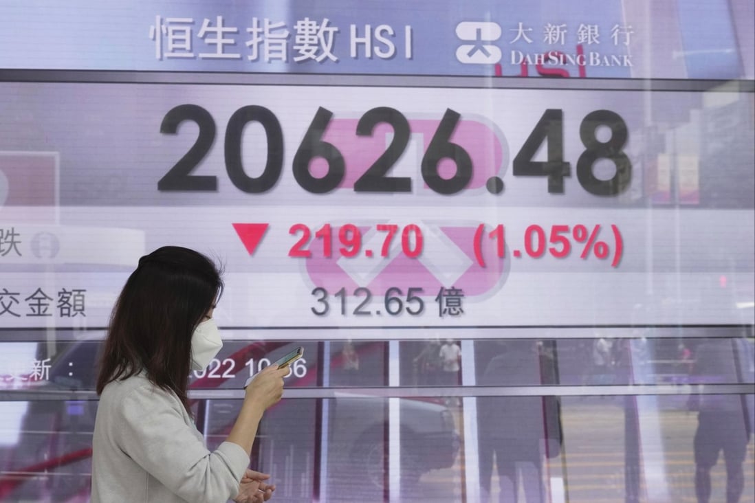 A woman walks past a bank’s electronic board showing the Hang Seng Index on July 19. Photo: AP