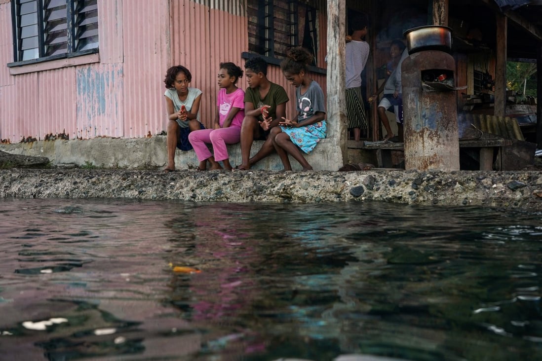 Children sit in front of a house next to a flooding sea wall in Fiji last month.  Photo: Reuters