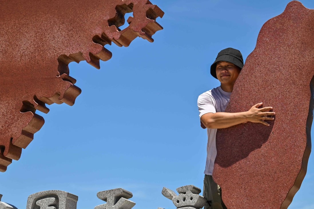 A tourist poses with a monument representing mainland China and Taiwan on Pingtan island in Fujian province, on August 6. Photo: AFP