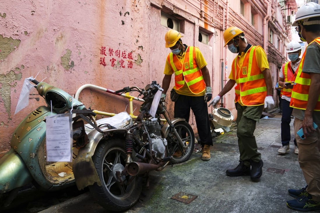 Contractors called in to remove an abandoned motorbike in an alley. Photo: Sam Tsang