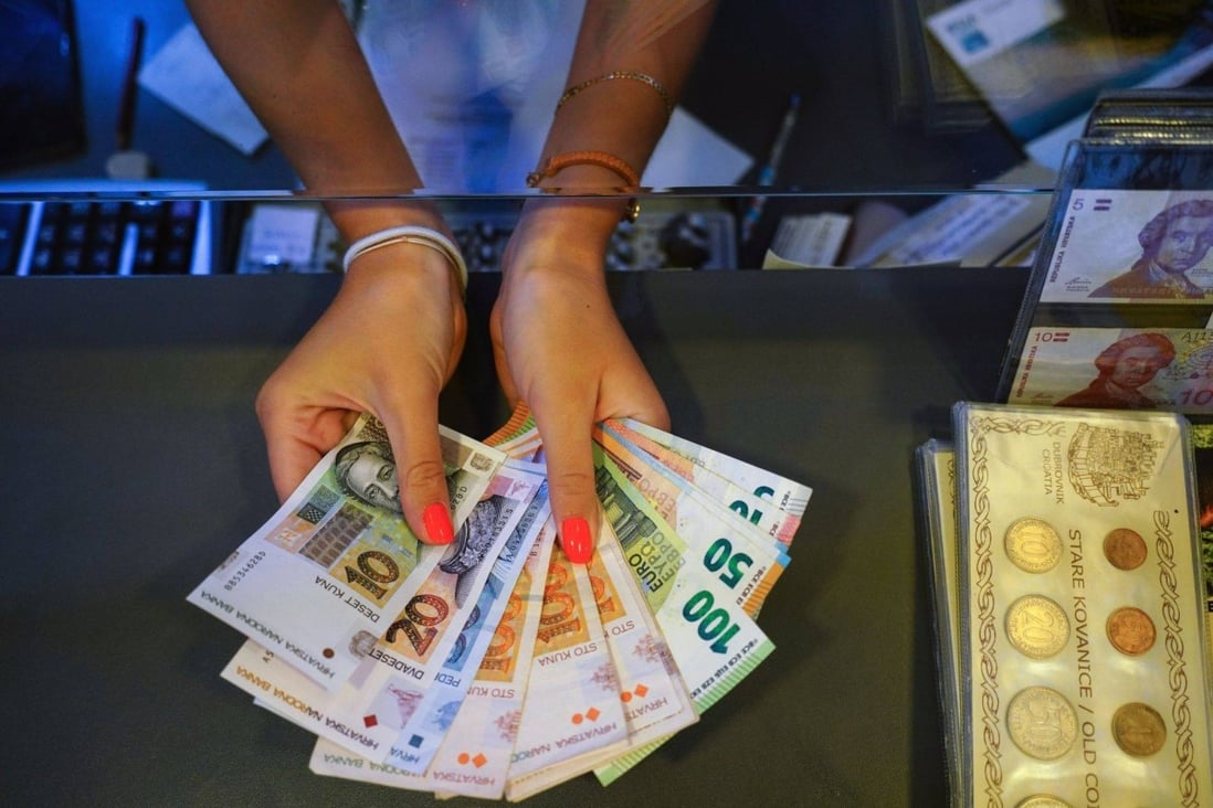 An employee shows Croatian kuna and euro banknotes at a currency exchange office in Dubrovnik, Croatia, on July 23. The euro is under increasing pressure on multiple fronts. Photo: Bloomberg