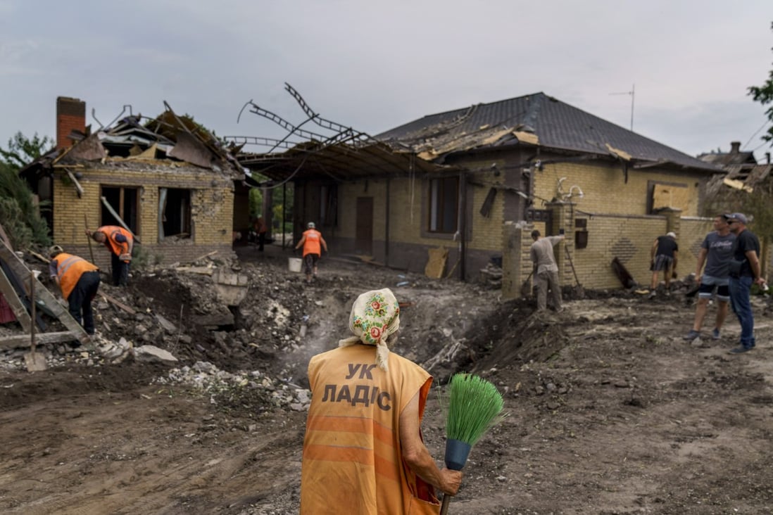An elderly worker with a broom inspects a crater caused by a rocket strike on a house in Kramatorsk, Donetsk region, eastern Ukraine. Photo: AP