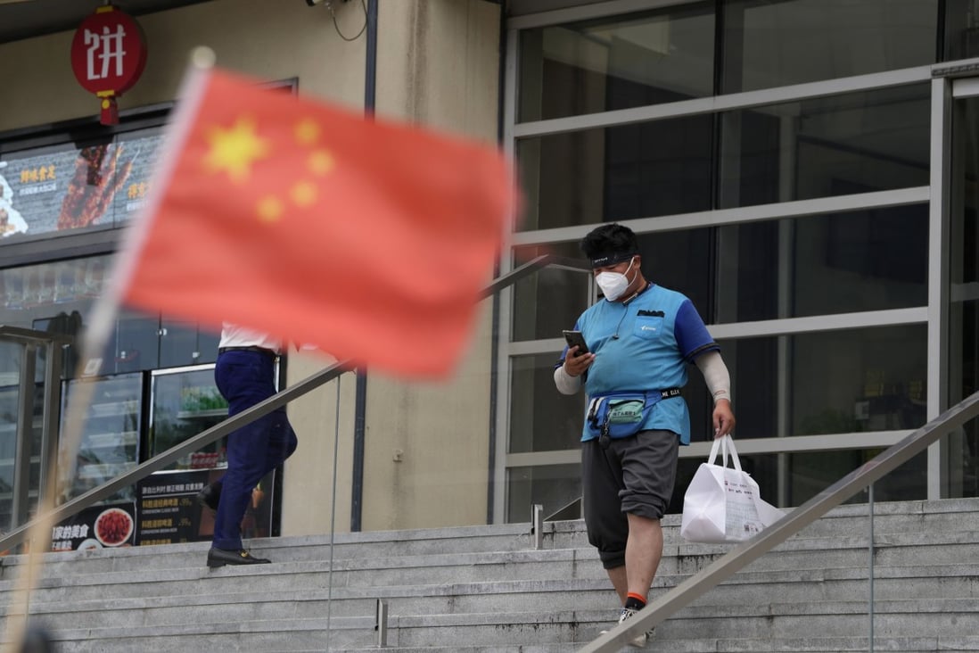 A delivery man walks near a Chinese flag in Beijing on Monday. Photo: AP Photo