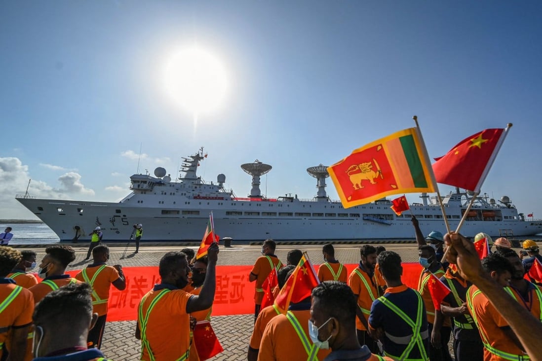 Workers wave the Chinese and Sri Lankan national flags as the Yuan Wang 5 docks at Hambantota port on Tuesday. Photo: AFP