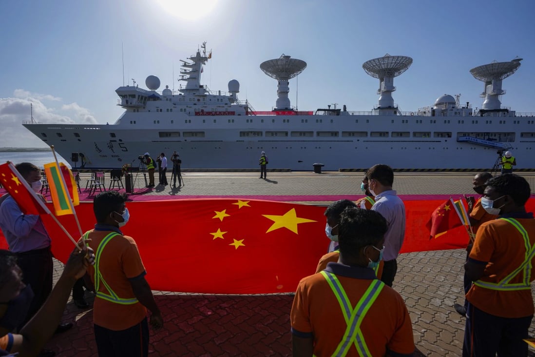 Sri Lankan port workers hold a Chinese national flag as they welcome the Yuan Wang 5 to Hambantota on August 16.   Photo: AP