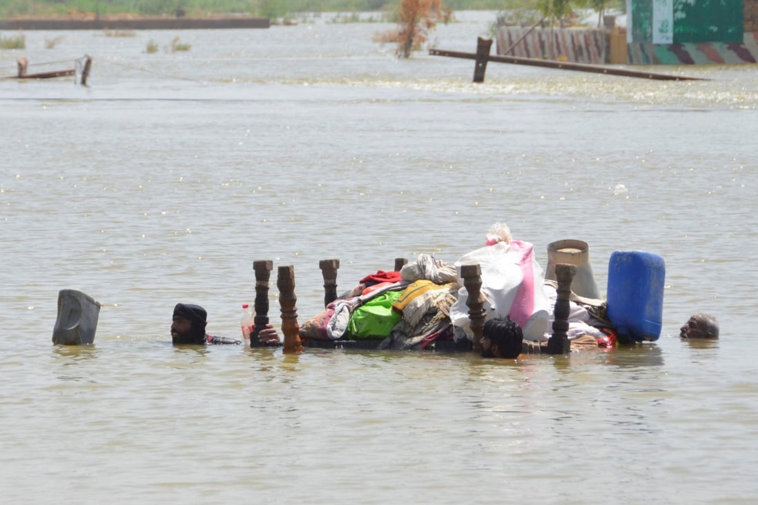Three flood victims float their belongings on an upturned table following heavy rains during the monsoon season in Dera Allah Yar, Jafferabad district, Pakistan, on September 5. Photo: Reuters