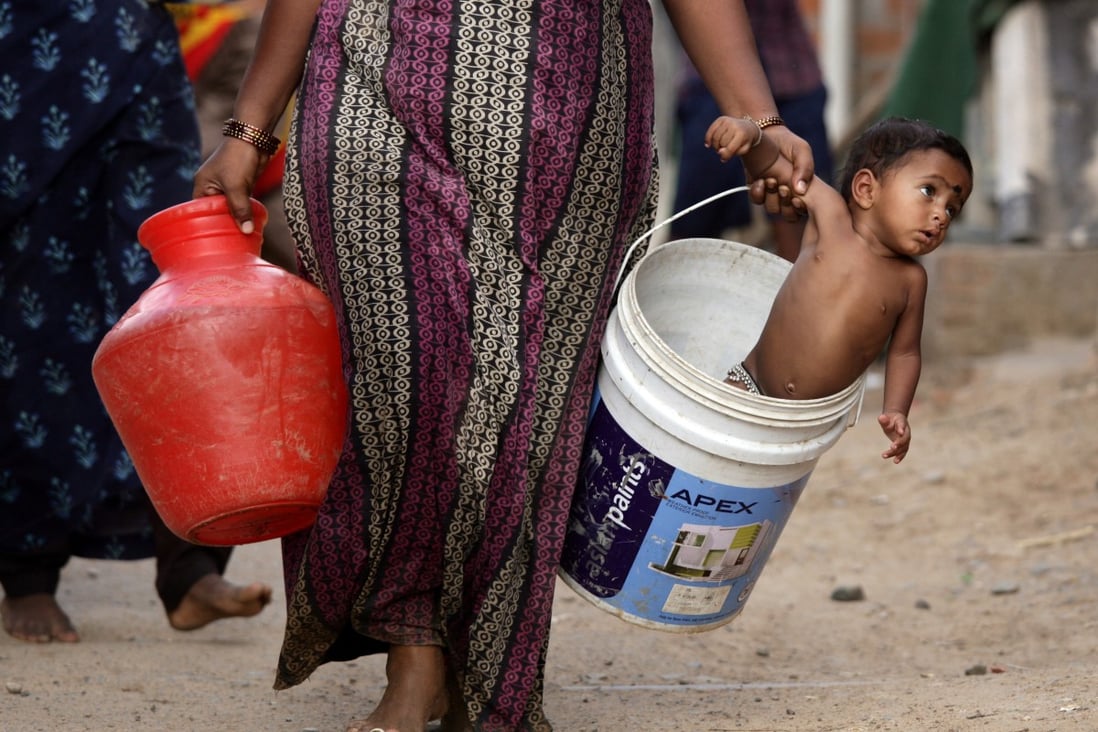 A woman carries her son in a bucket after collecting water from a municipal tanker on the outskirts of Chennai, India, on July 4, 2019. Photo: Reuters