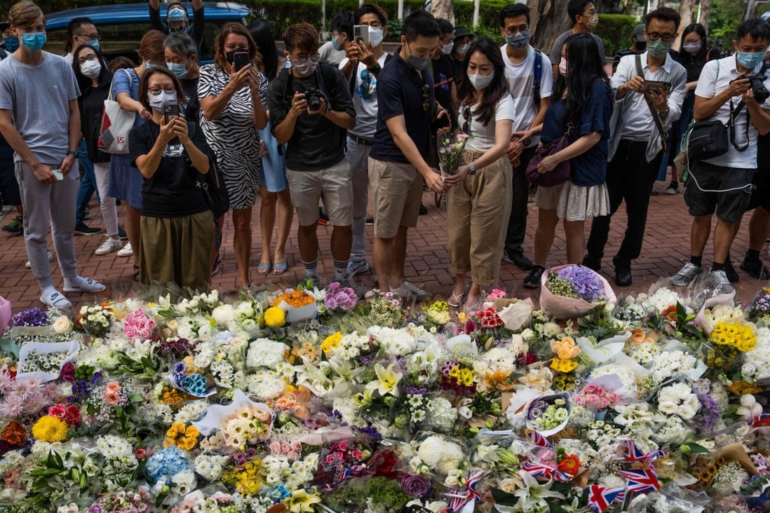 People gather next to flowers placed as a tribute for Queen Elizabeth outside the British Consulate in Hong Kong on September 10. Photo: AFP