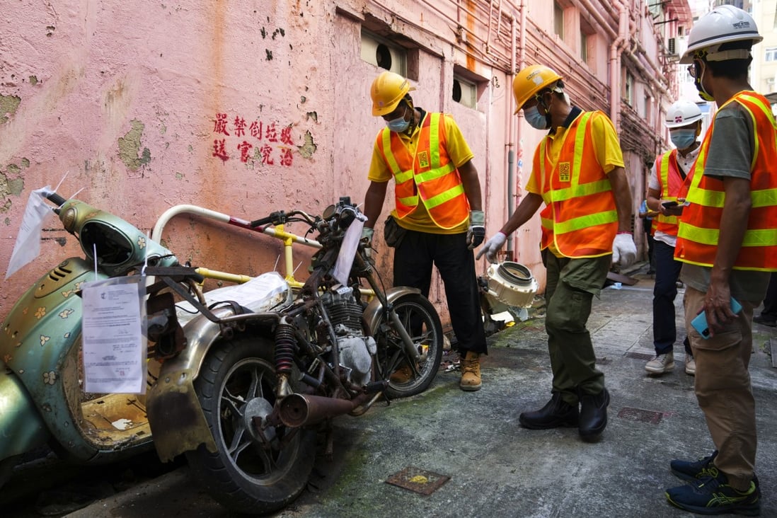 Contractors called in to remove an abandoned motorbike in an alley. Photo: Sam Tsang